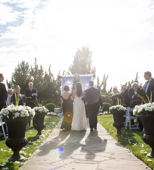 Bride being walked down the aisle at outdoor wedding ceremony