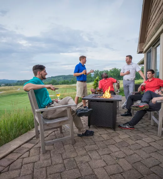 Group of guys enjoying drinks over a fire pit