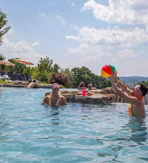 Woman and two men playing with a blow up ball in the Vista 180 pool.