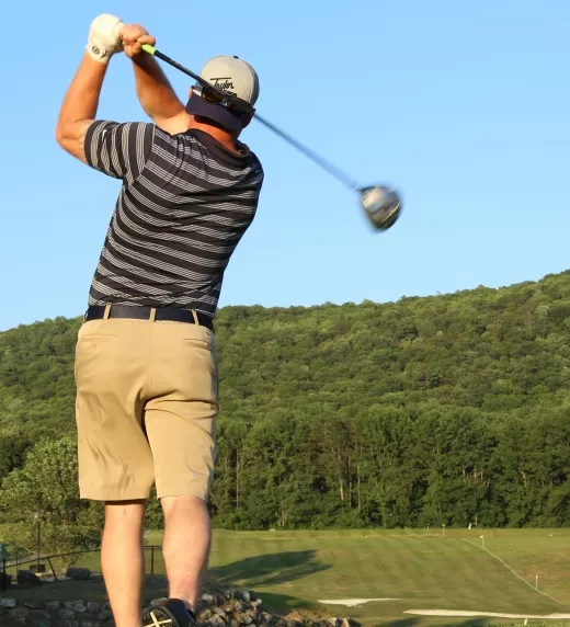Man teeing off at a driving range 