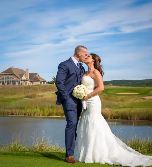 Bride and groom kissing in front of Ballyowen Golf Club