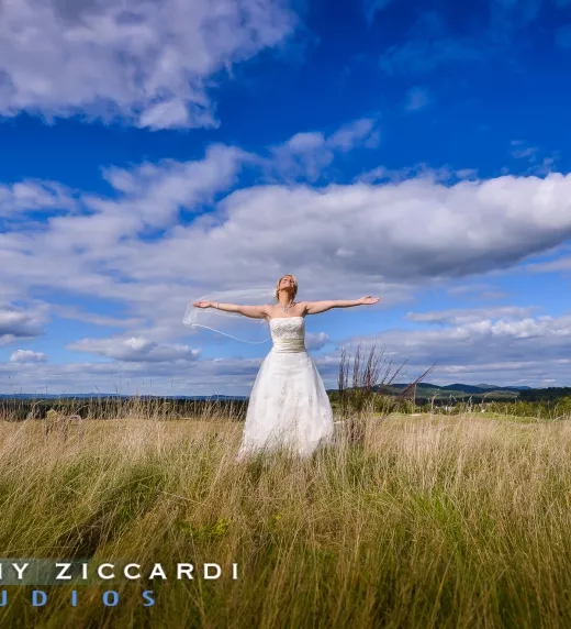 Bride extending arms in tall grass