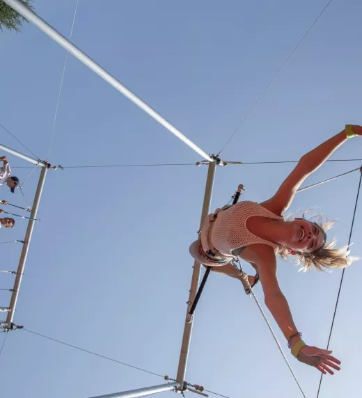 Woman flying trapeze outdoors.