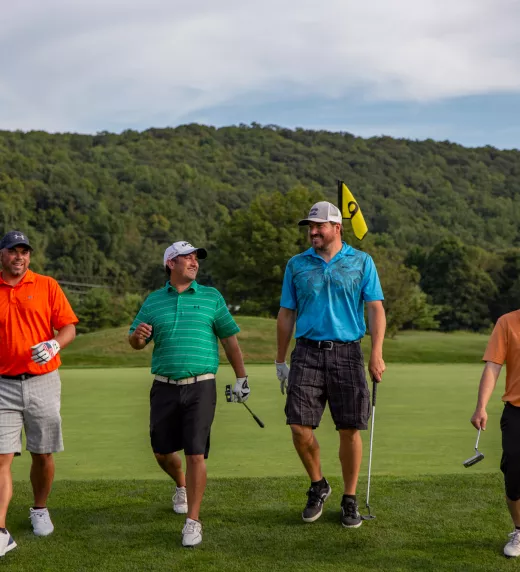 Four guys wearing multi-colored shirts walking on a golf course at a resort close to NYC