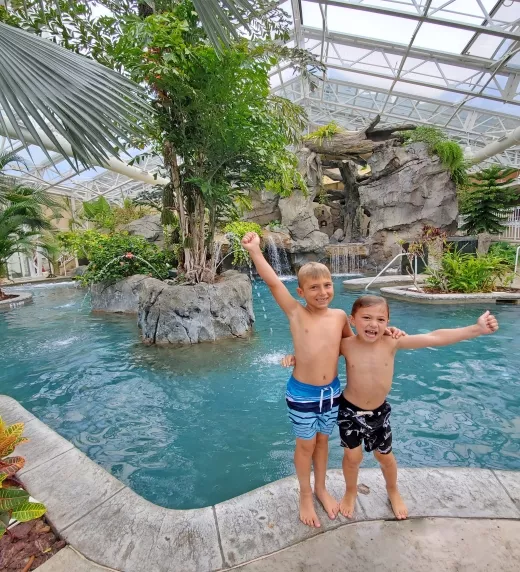 Two boys with their arms around eachother standing outside Biosphere pool.