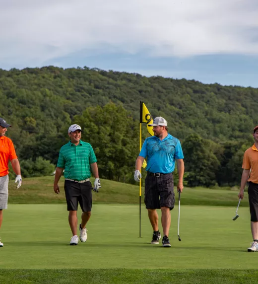 Four guys wearing multi-colored shirts walking on a golf course at a resort close to NYC