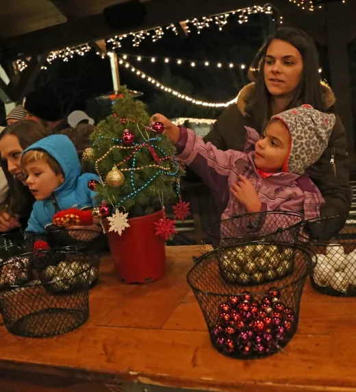 Young children decorating mini trees with bulbs.
