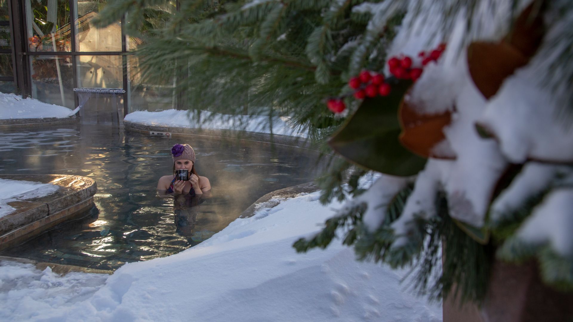 Woman drinking out of a mug in a snow pool.