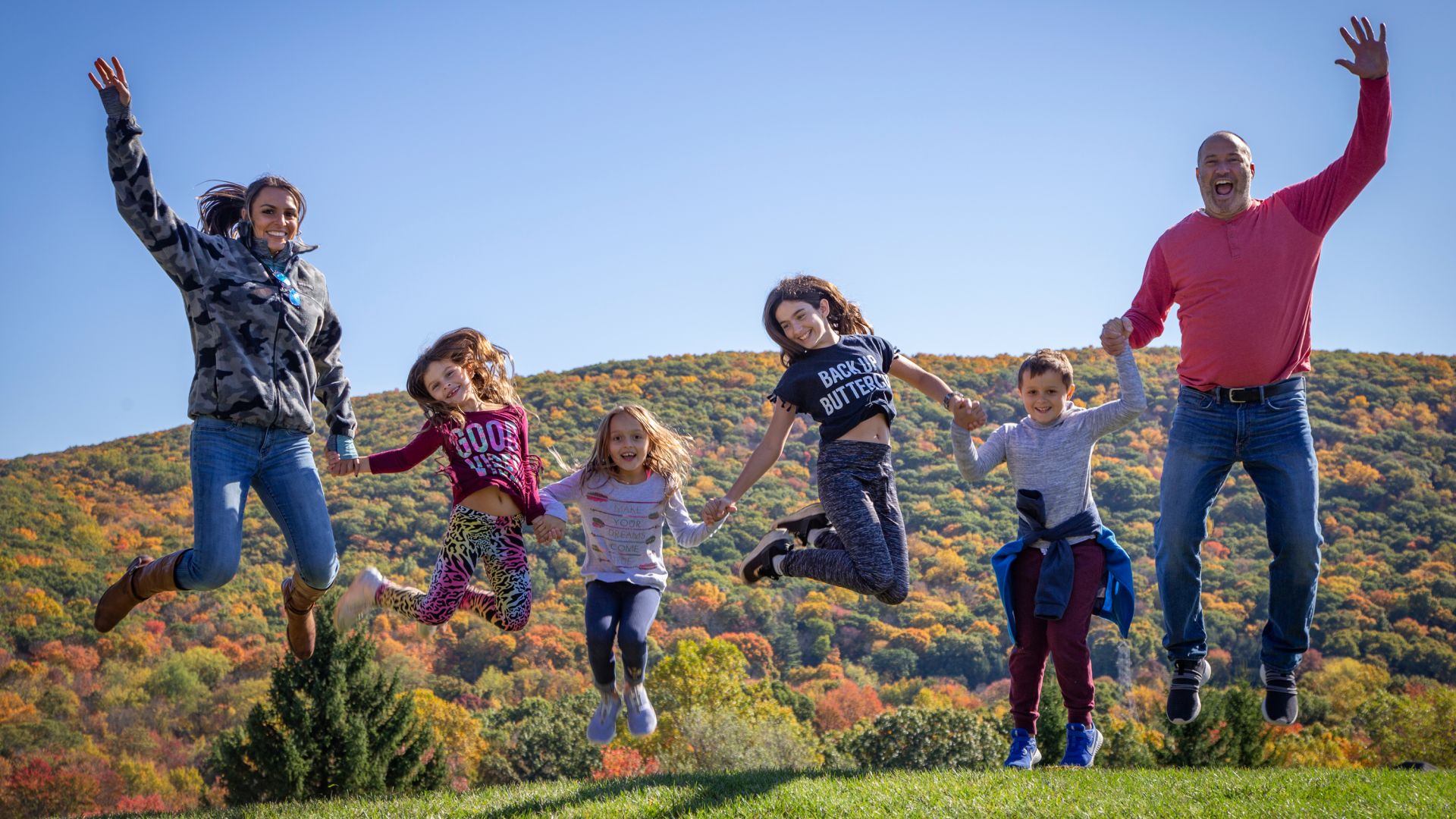 Family jumping in front of the beautiful color-changing mountain vistas.