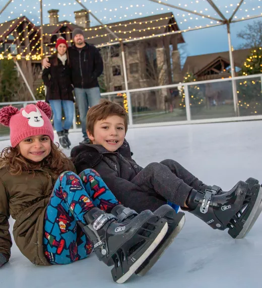 Kids sitting on glice skating rink.