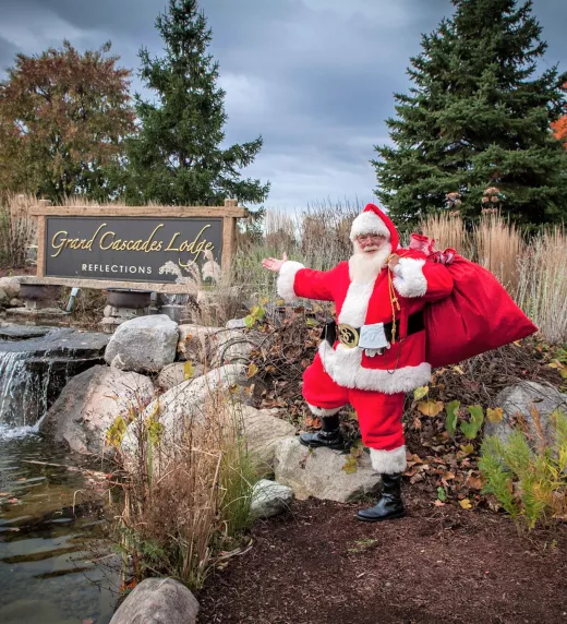 Santa posing in front of Grand Cascades Lodge Reflections Spa sign