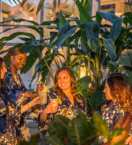 Four women in floral robes drinking in the Biosphere during girlfriends getaway.
