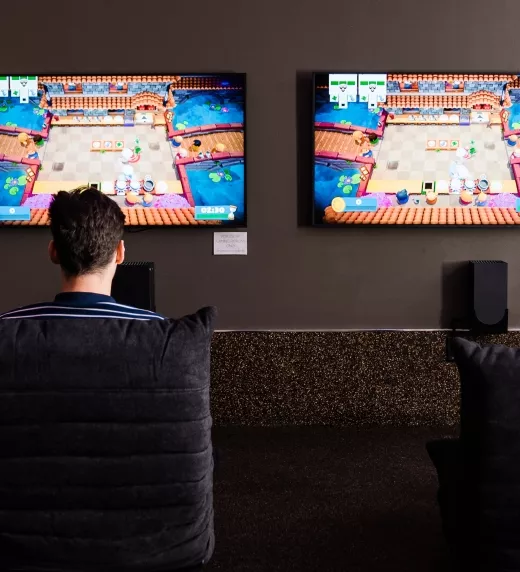 Two children sitting in front of two tvs playing video games.