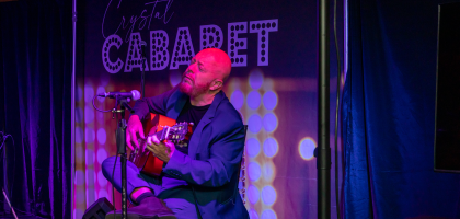 Hernan Romero playing guitar on stage at Crystal Cabaret.