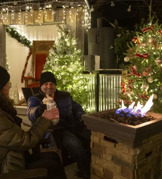Couple enjoying festive drinks around the fire at Frosty's Cantina