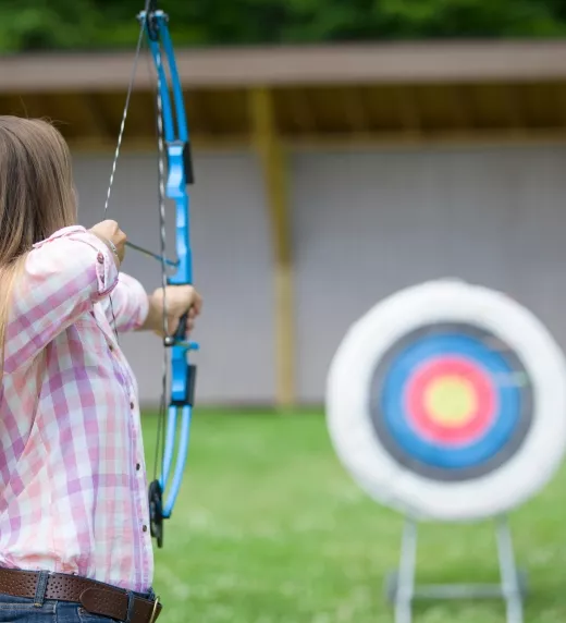 Woman on archery range shooting at target.