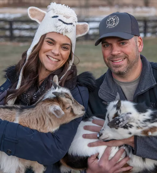 Couple holding baby goats.