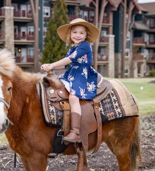 Young girl riding a pony during family vacation.