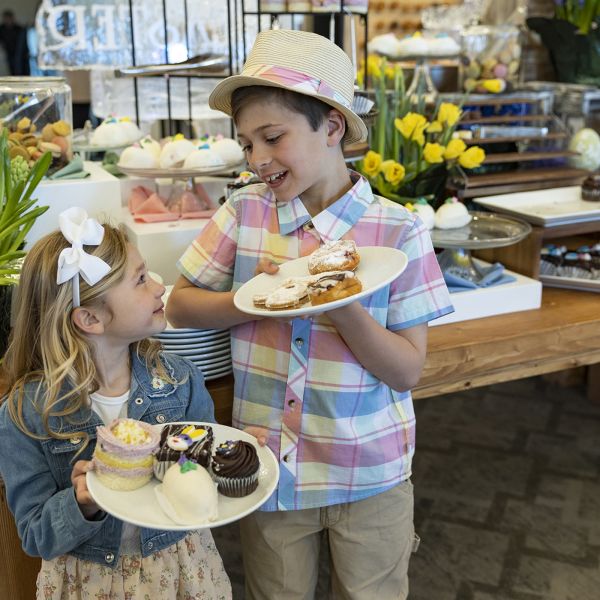 Two children looking at each other holding plates of desserts.