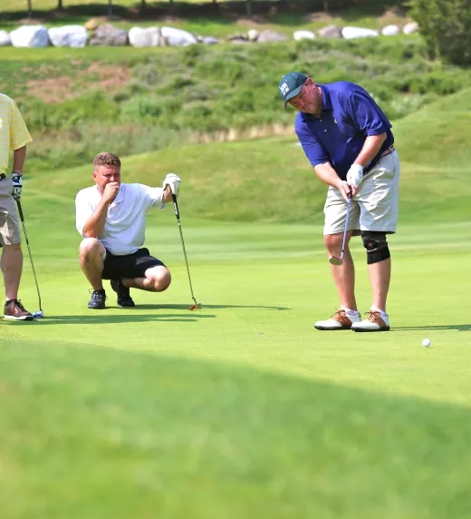 A foursome of guys on the putting green of a golf course at Crystal Springs Resort